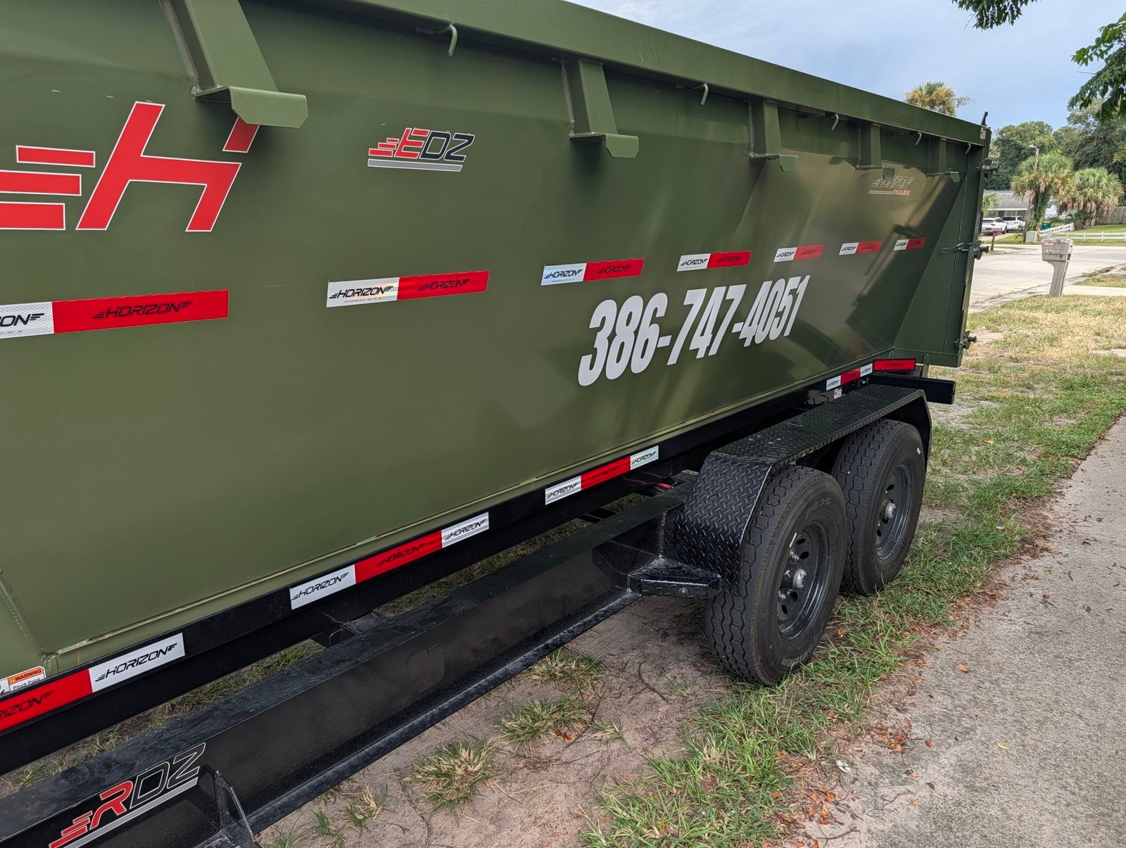 Custom phone number and logo vinyl lettering on a roll-off dumpster
